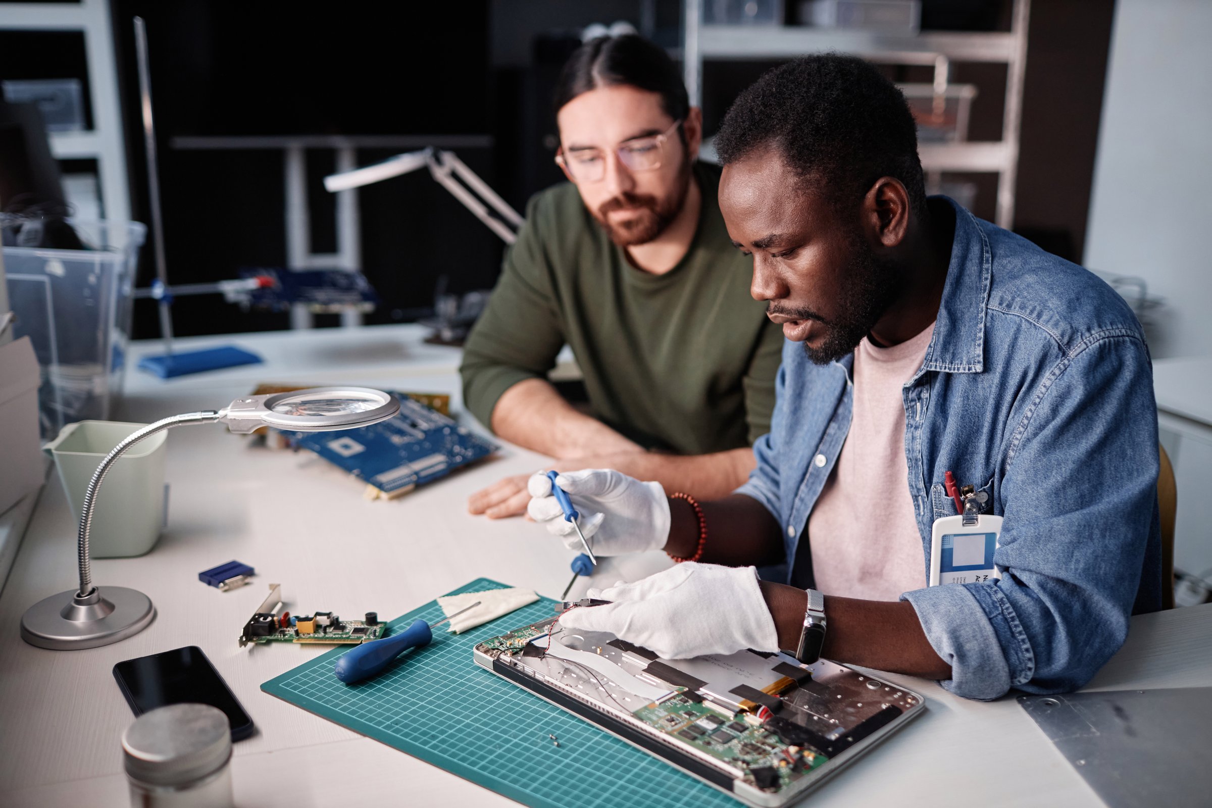 Portrait of two workers fixing computer in tech repair shop, copy space