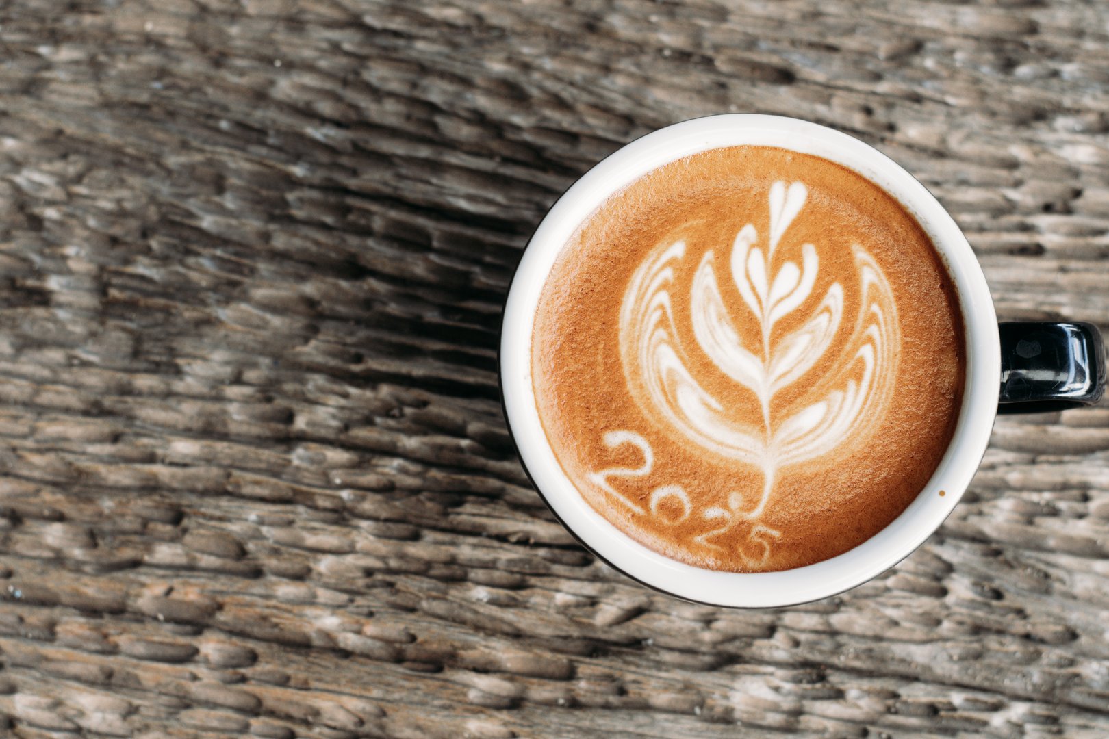 hot coffee with foam milk art 2025 on wooden table