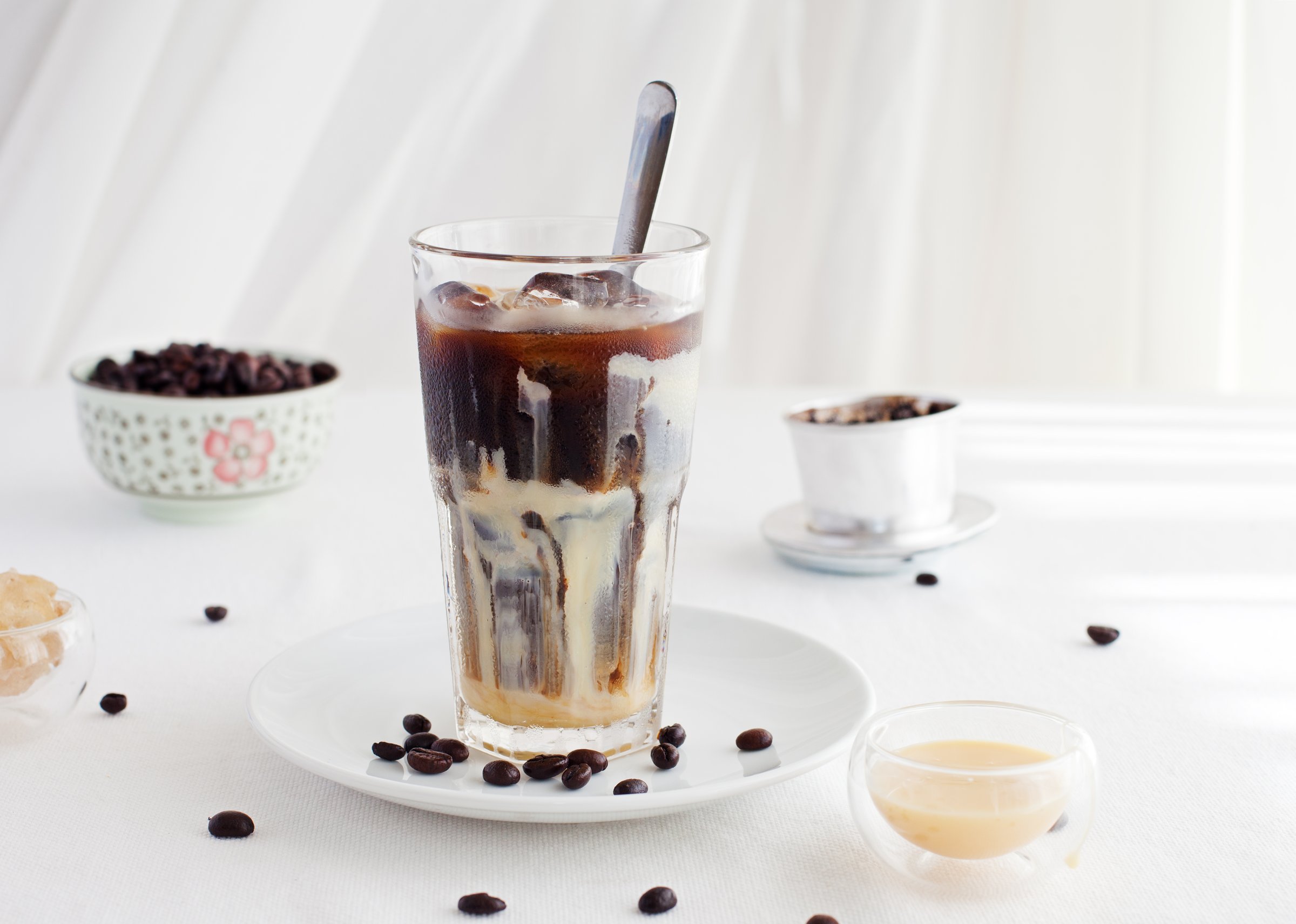 Ice coffee with condensed milk, traditional Vietnamese, Thai coffee with coffee beans on a white plate background