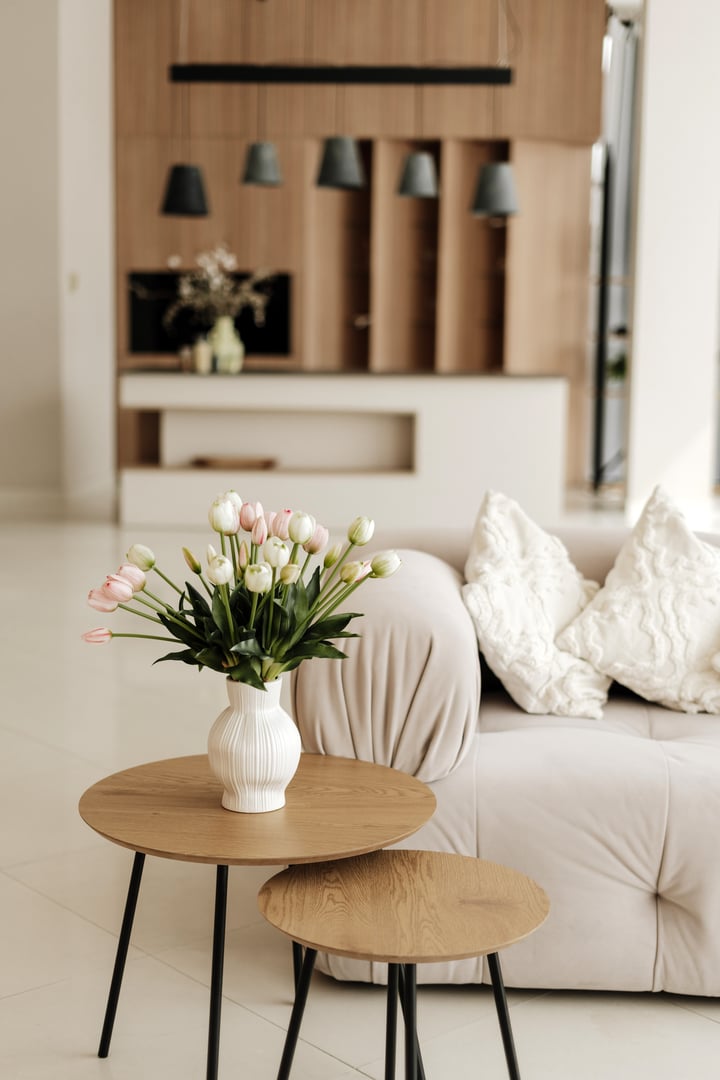 Bouquet of pink and white tulips is standing on a coffee table in a modern living room, bringing a touch of spring freshness to the interior design