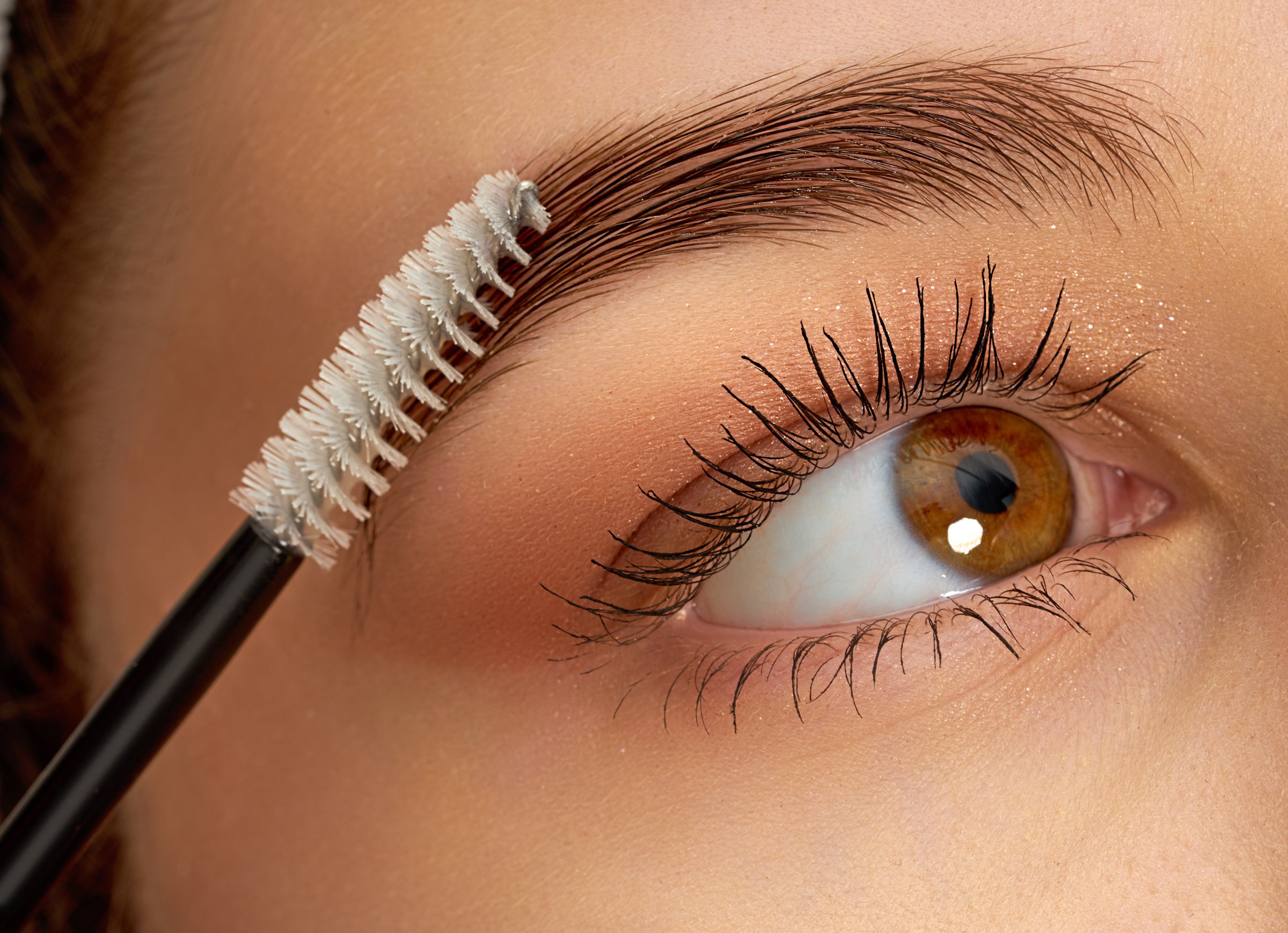 Makeup artist combs eyebrows with a brush . Professional makeup and cosmetology skin care. Close up