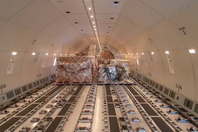 Interior of a cargo airplane with freight pallets secured on the floor, showing a spacious and organized layout.