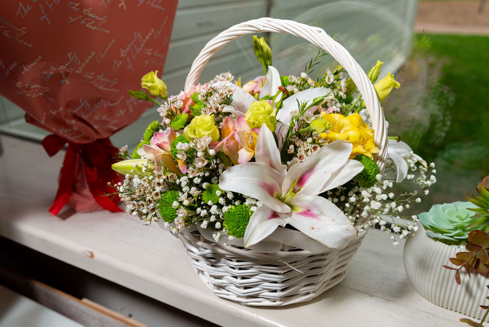 A beautifully arranged basket overflowing with lilies, roses, and lush greenery, perfect for special occasions or as a charming home decoration. essence of natural beauty.