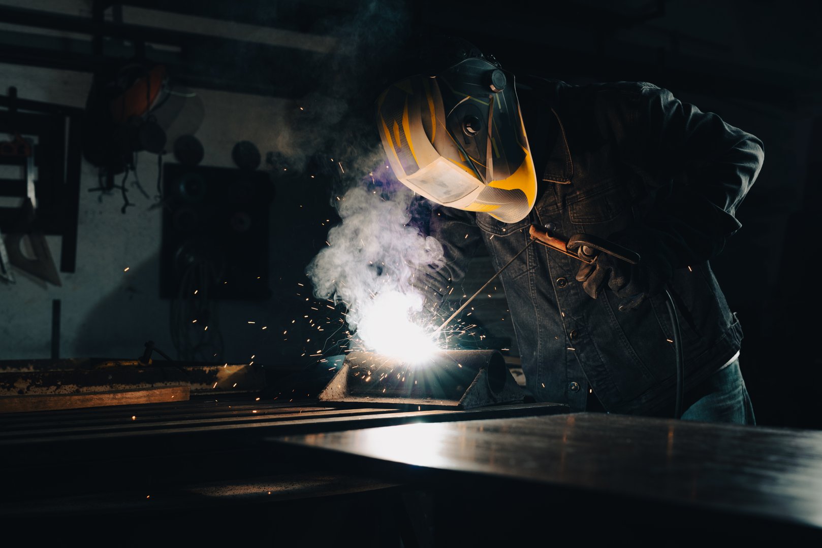 Worker welding an iron plate on the workbench in the workshop