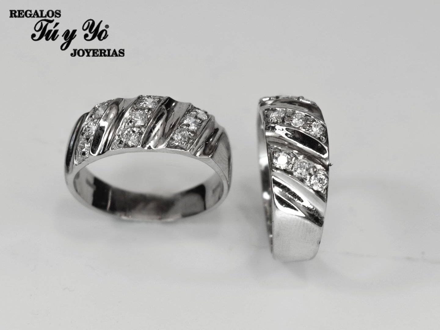 Two silver rings with diagonal stripes and small diamonds arranged in a row, labeled with 'REGALOS Tú y Yo JOYERIAS.'