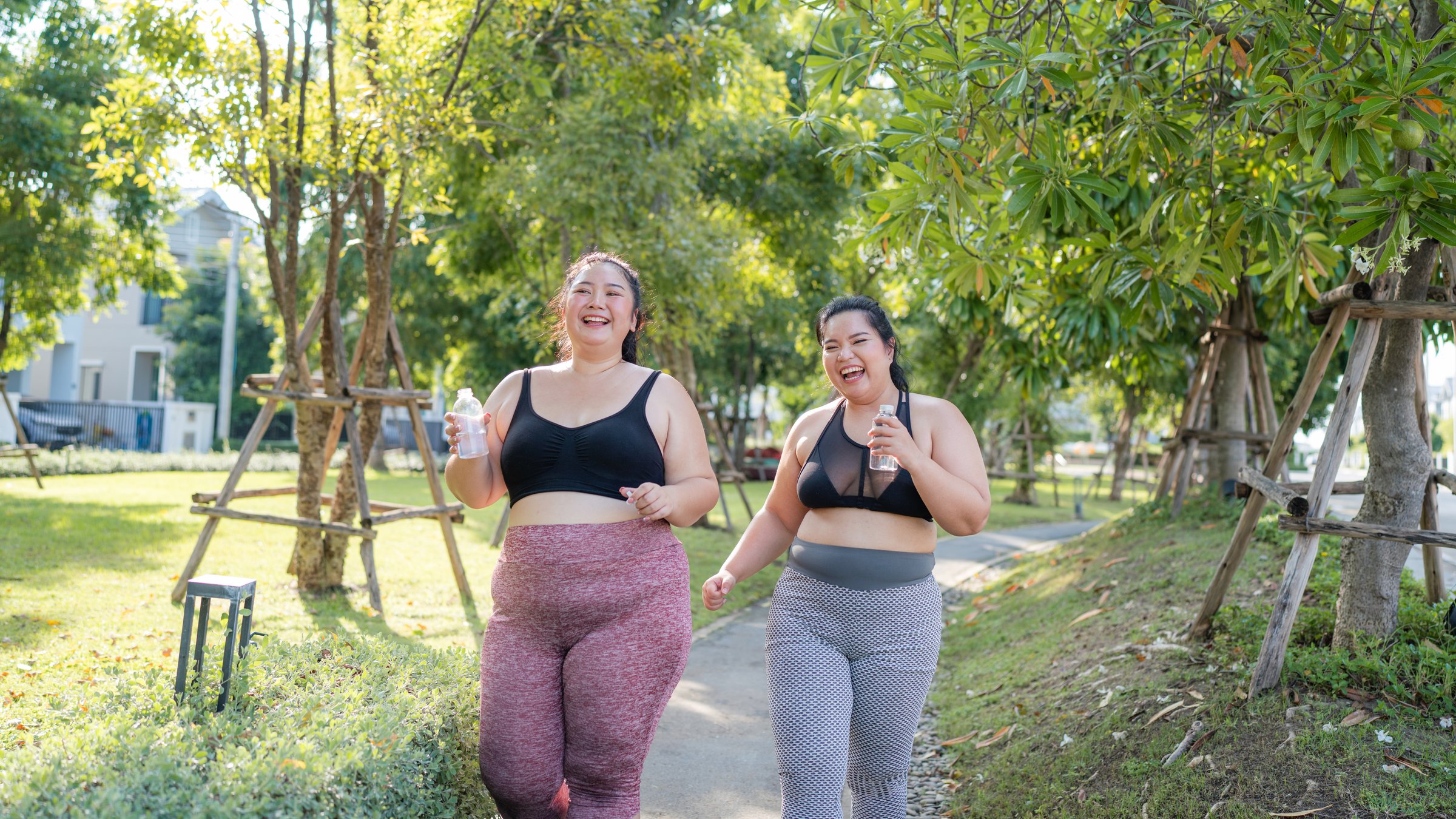 Happy plus size asian woman running in a park for health, wellness and outdoor exercise. Nature, sports and female athlete runner doing cardio workout in garden. Healthy Concept.