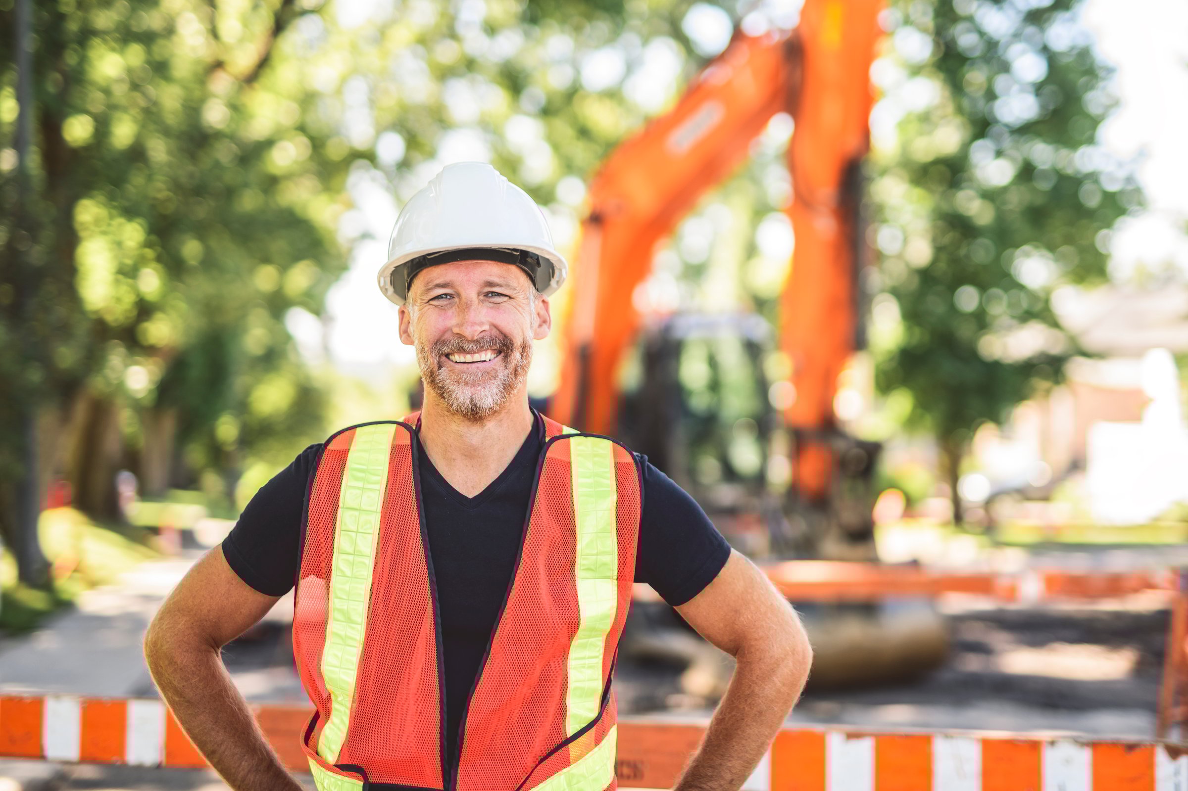 A caucasian engineer with white helmet at work and having a mechanical shovel on the back