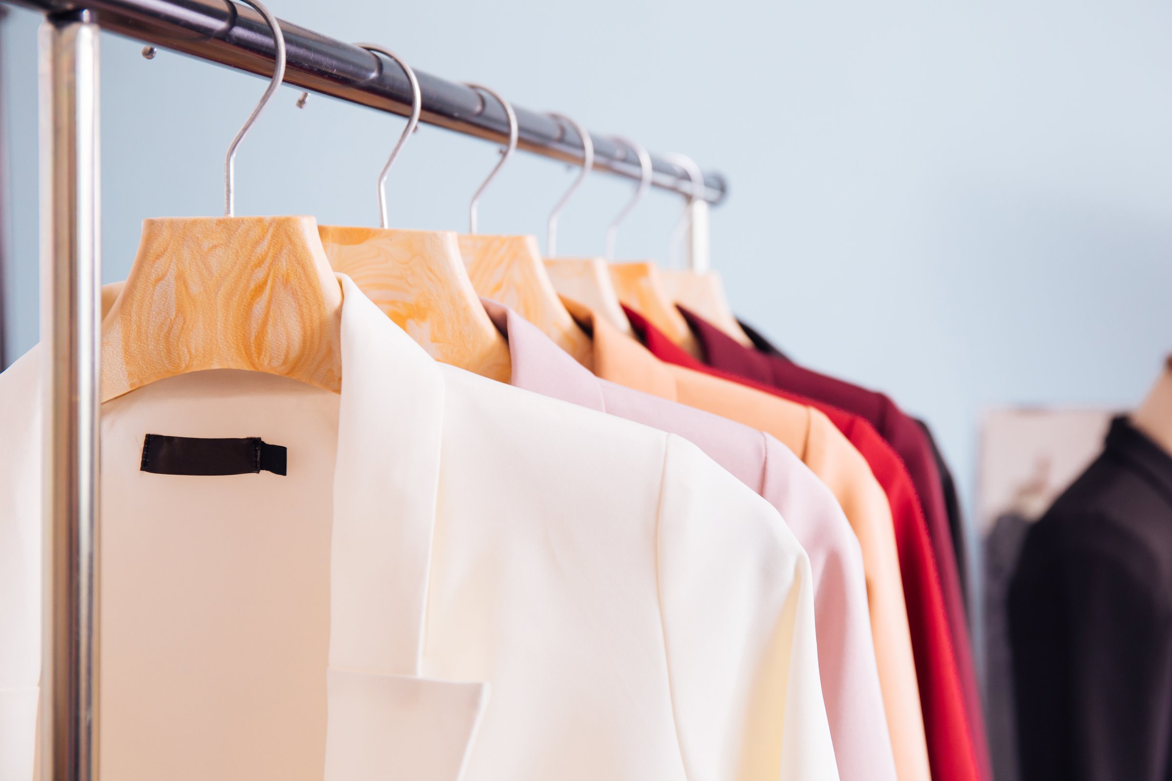 Close up of many colors of fashionable business suits hanging on rack for sale in store