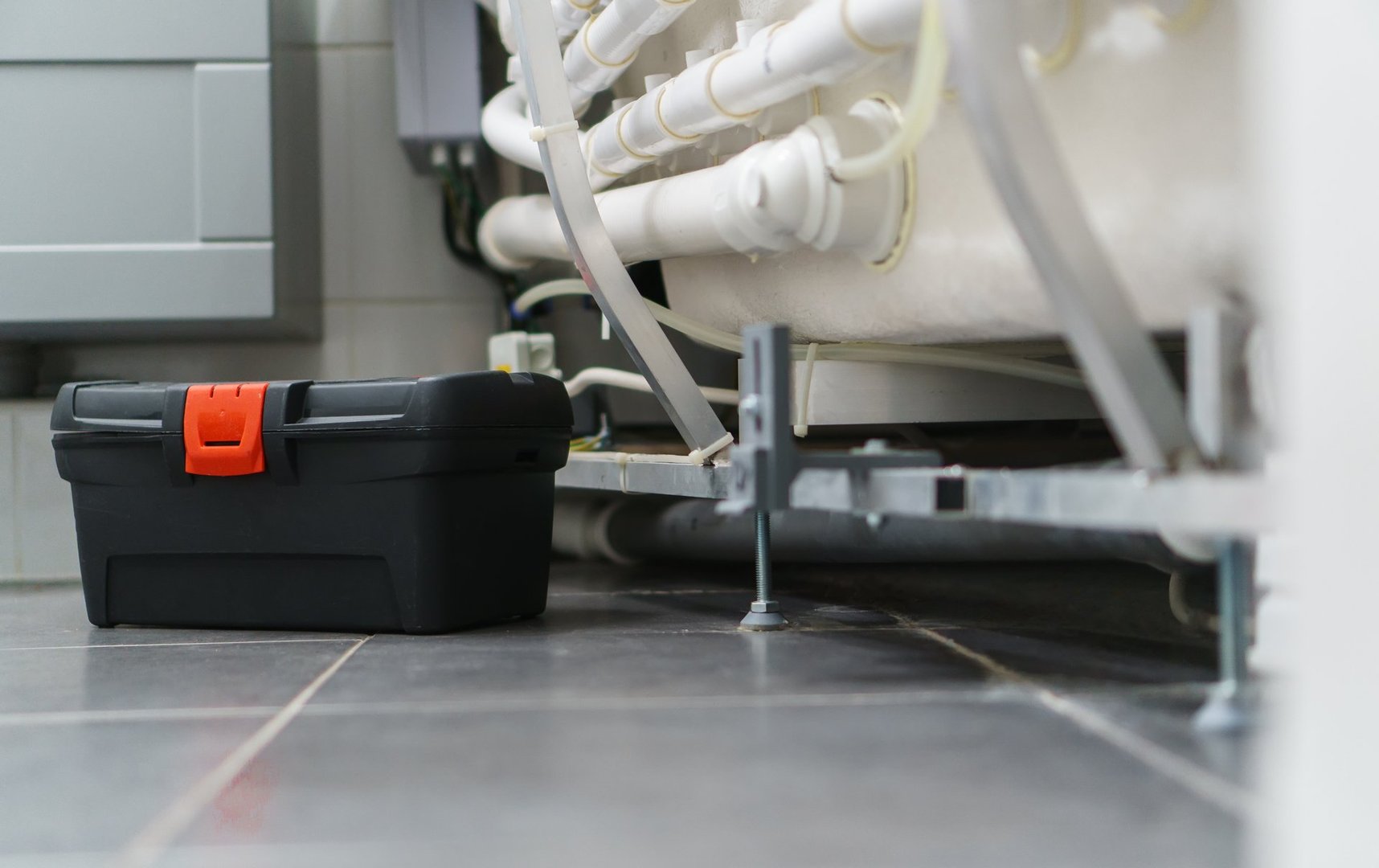 Toolbox near pipe system of bathtub with hydromassage.