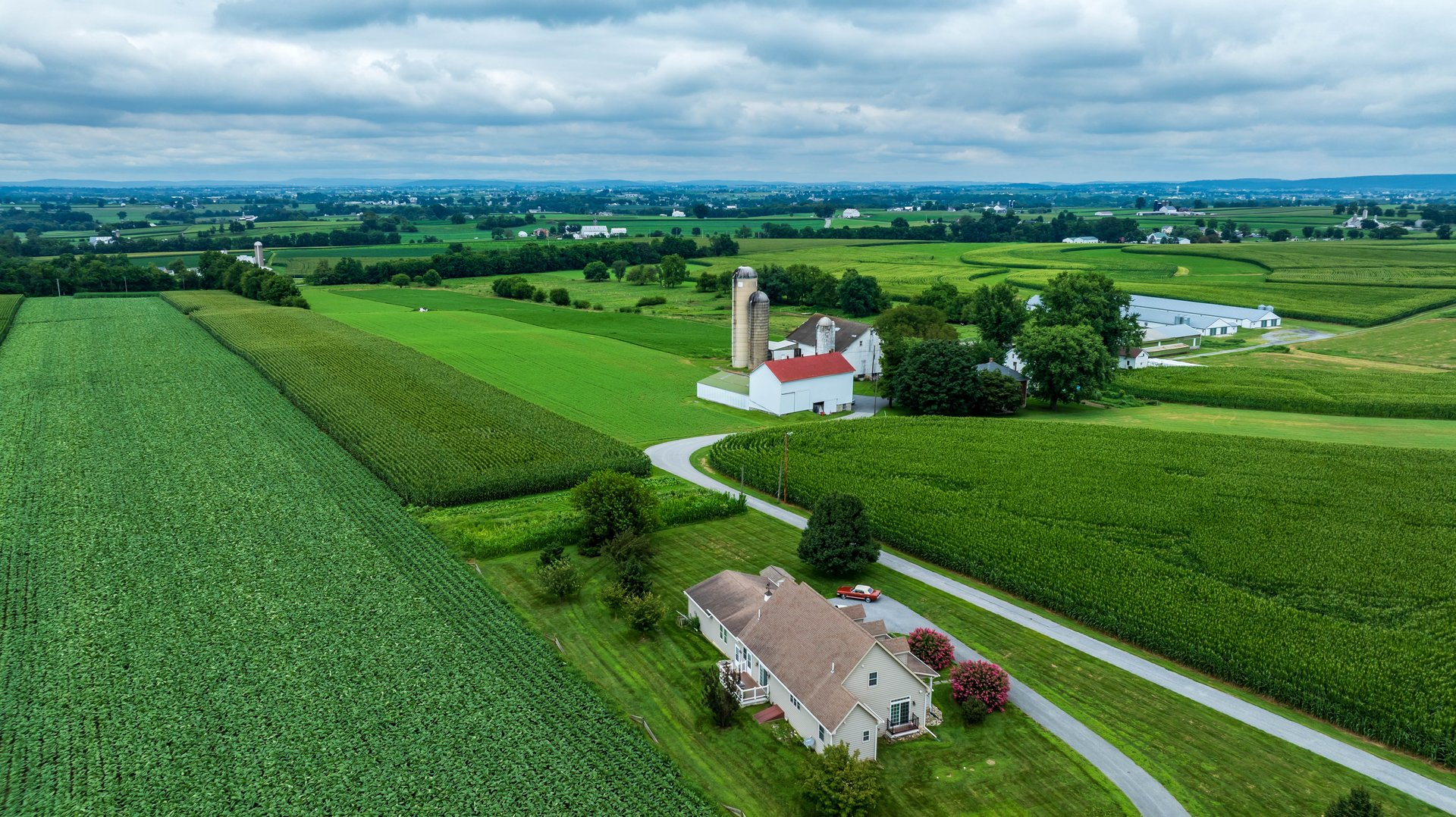 Een vredige landelijke scene met een boerderij met weelderig groene velden en een rode schuur.