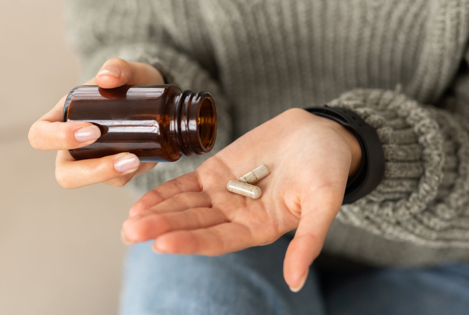 Closeup hands of young woman holding medicine herbs capsules, cropped of lady taking supplement product or vitamin type capsule. Nutrition for women, healthcare, drugs