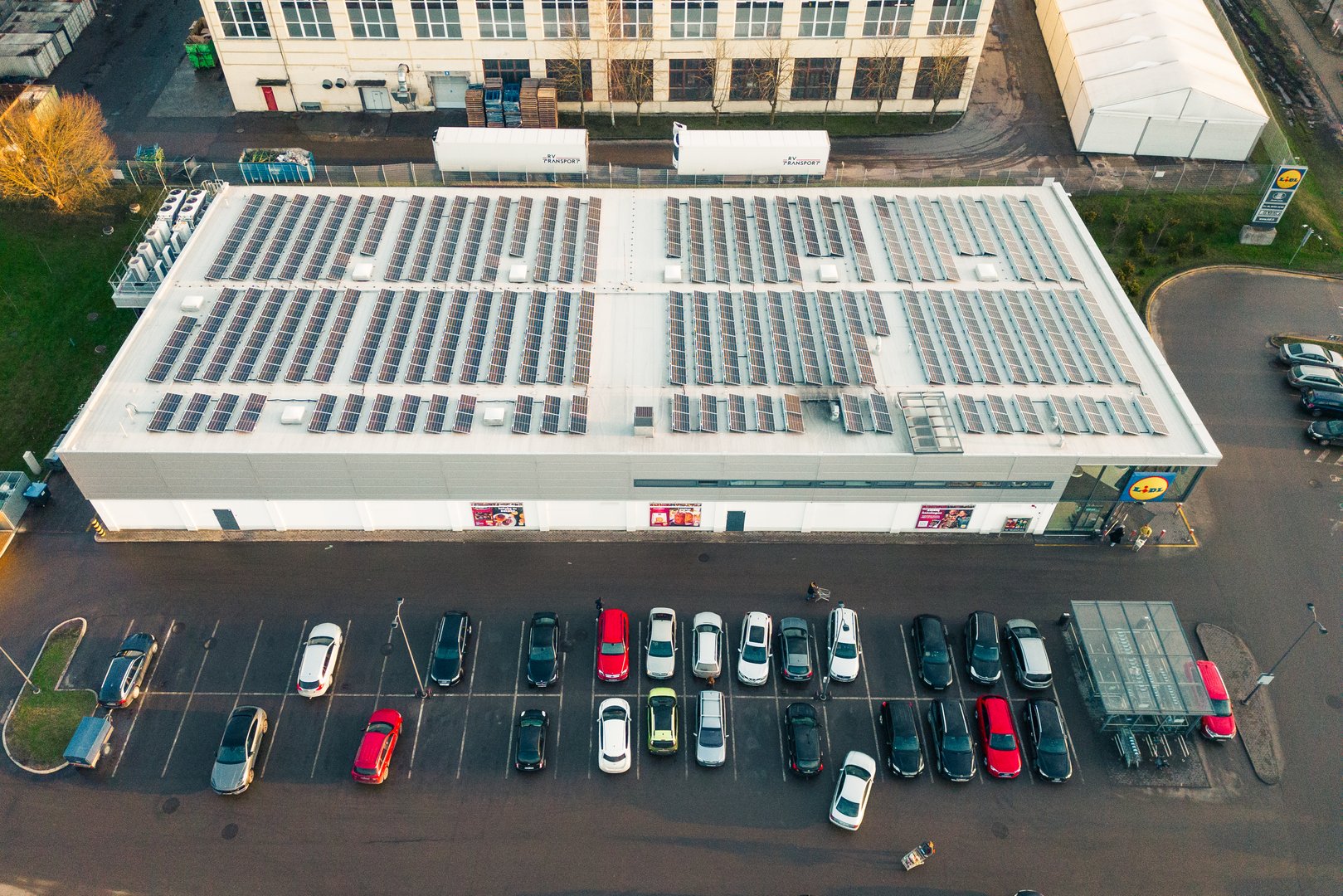 Siauliai, Lithuania - 17th november, 2024: Aerial top down cars in parking and customers go do shopping to german Lidl supermarket building with solar panels on rooftop.Sustainability business concept