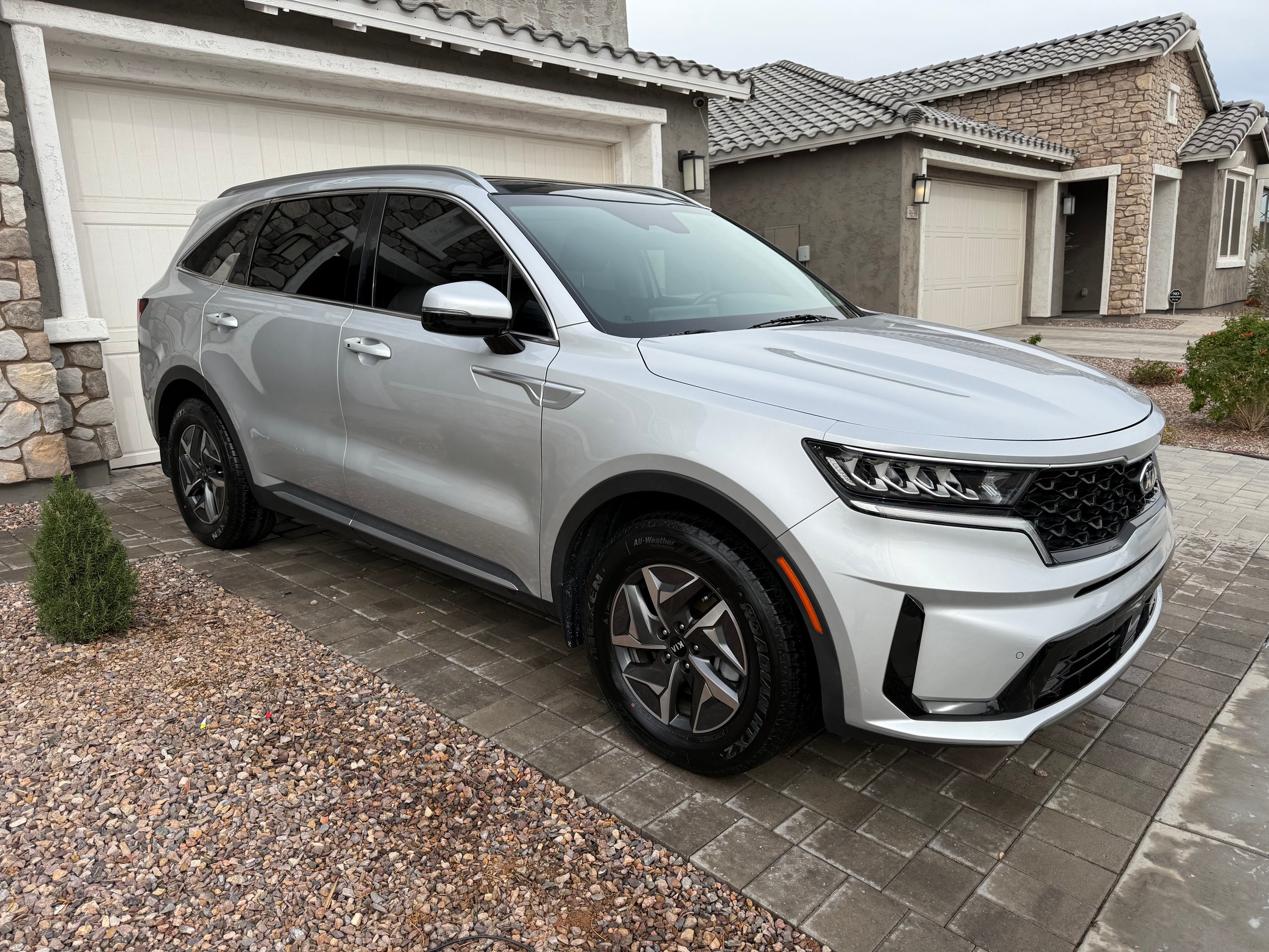 Silver SUV parked on a driveway in front of a stone and stucco house, with tiled roof and multiple garages.