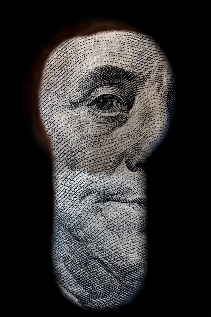 Benjamin Franklin looking through the keyhole, close up. The eye of the president of America on the hundred dollar bill looks through the keyhole