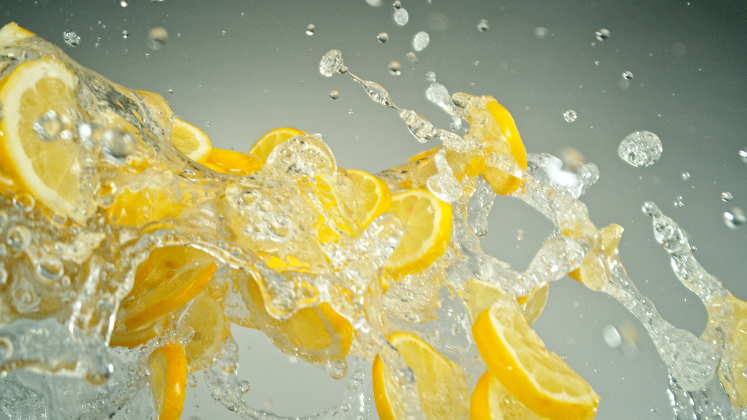 Freeze Motion of Flying Slices of Lemons with Splashing Water. Isolated on Grey Background, closeup.