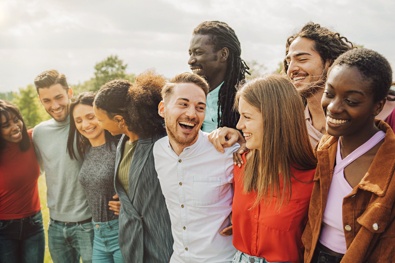 Group of young friends of different races and cultures have carefree fun playing piggyback together outdoors - youth culture lifestyle concept