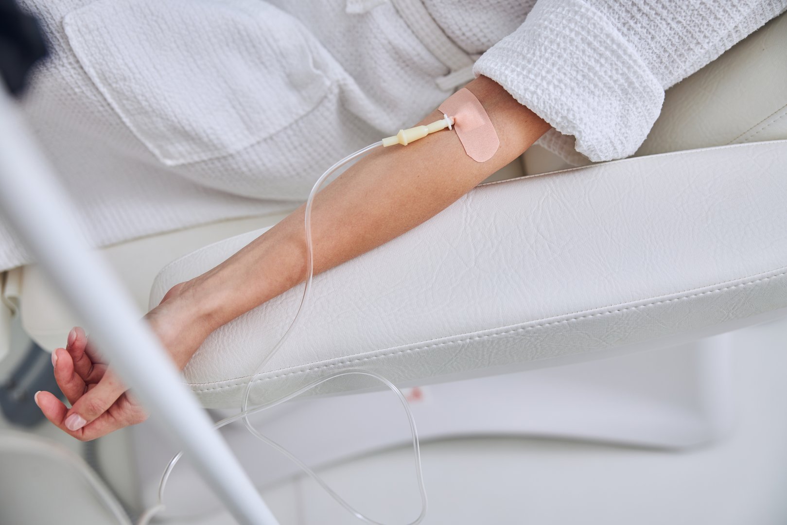 Cropped head portrait of unrecognized female patient receiving vitamin intravenous drip treatment in wellness clinic