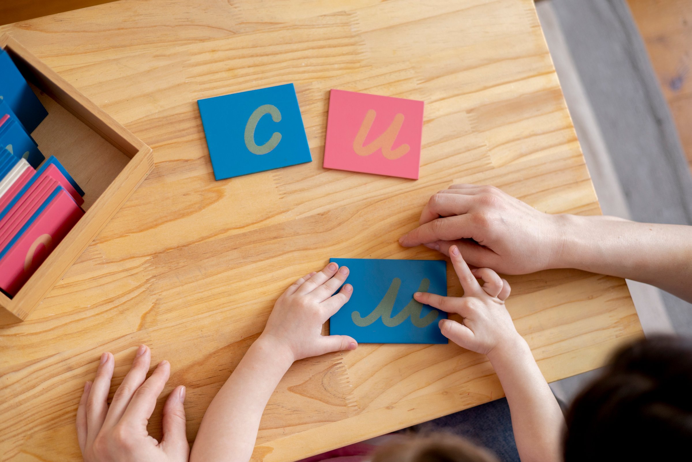 Montessori material. Mom helps her daughter learn letters using the rough alphabet. Child toddler girl. Concept of learning. Development of motor skills.