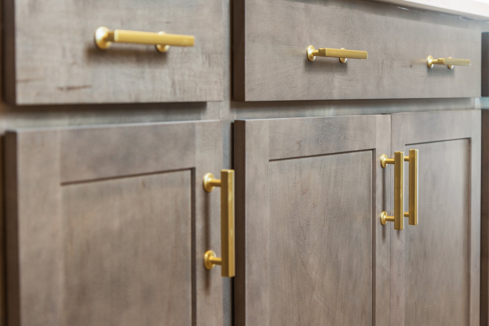 Gold hardware handles on tan kitchen cabinets
