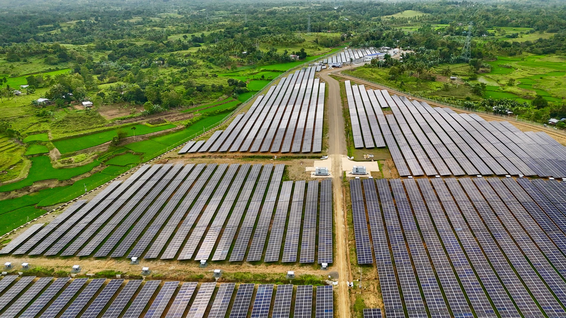 Solar panels sunny day green fields blue sky aerial view