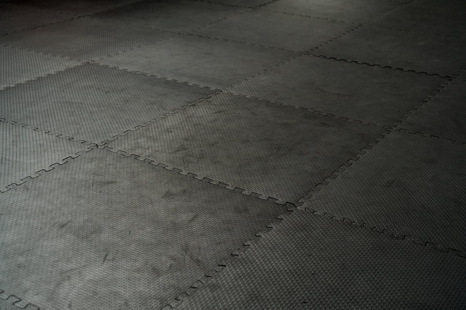 Black rubber floor mat and tiles inside a gym. Black rubber fitness floor texture and background. EPDM safety mats reduce the injury risk caused by falls on playgrounds and sport facilities.