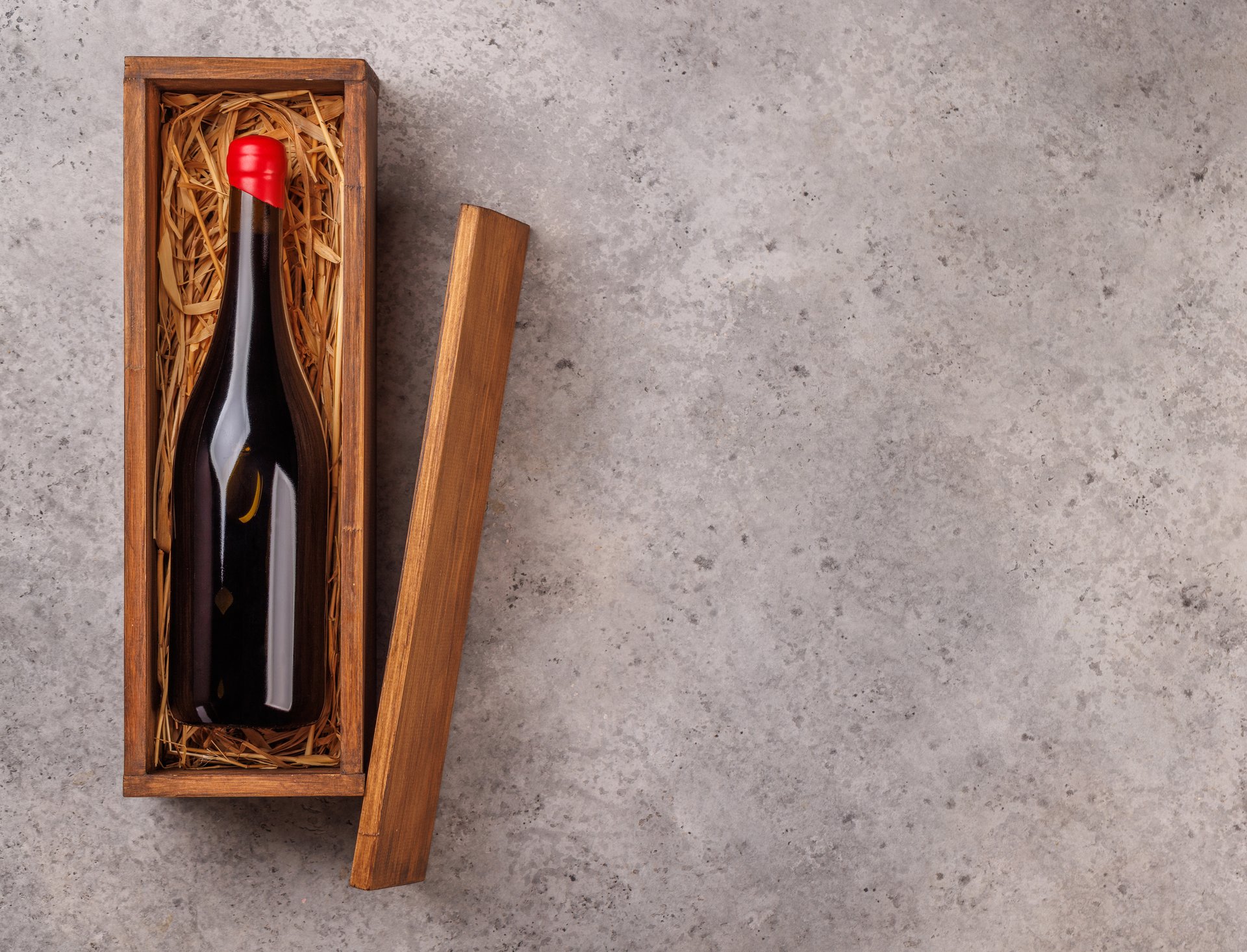 A red wine bottle elegantly placed inside a rustic wooden box, creating a classic and sophisticated presentation. Perfect for wine lovers, gift packaging, or cellar storage
