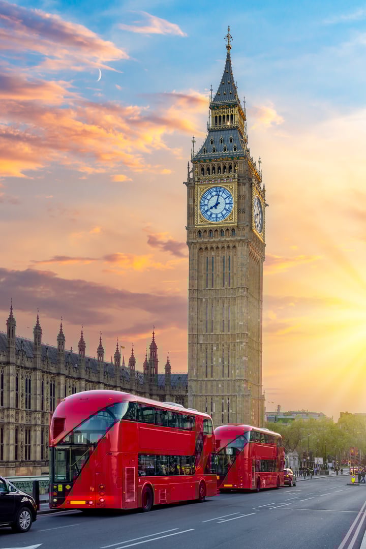 Big Ben tower and double-decker buses on Westminster bridge at sunset, London, UK