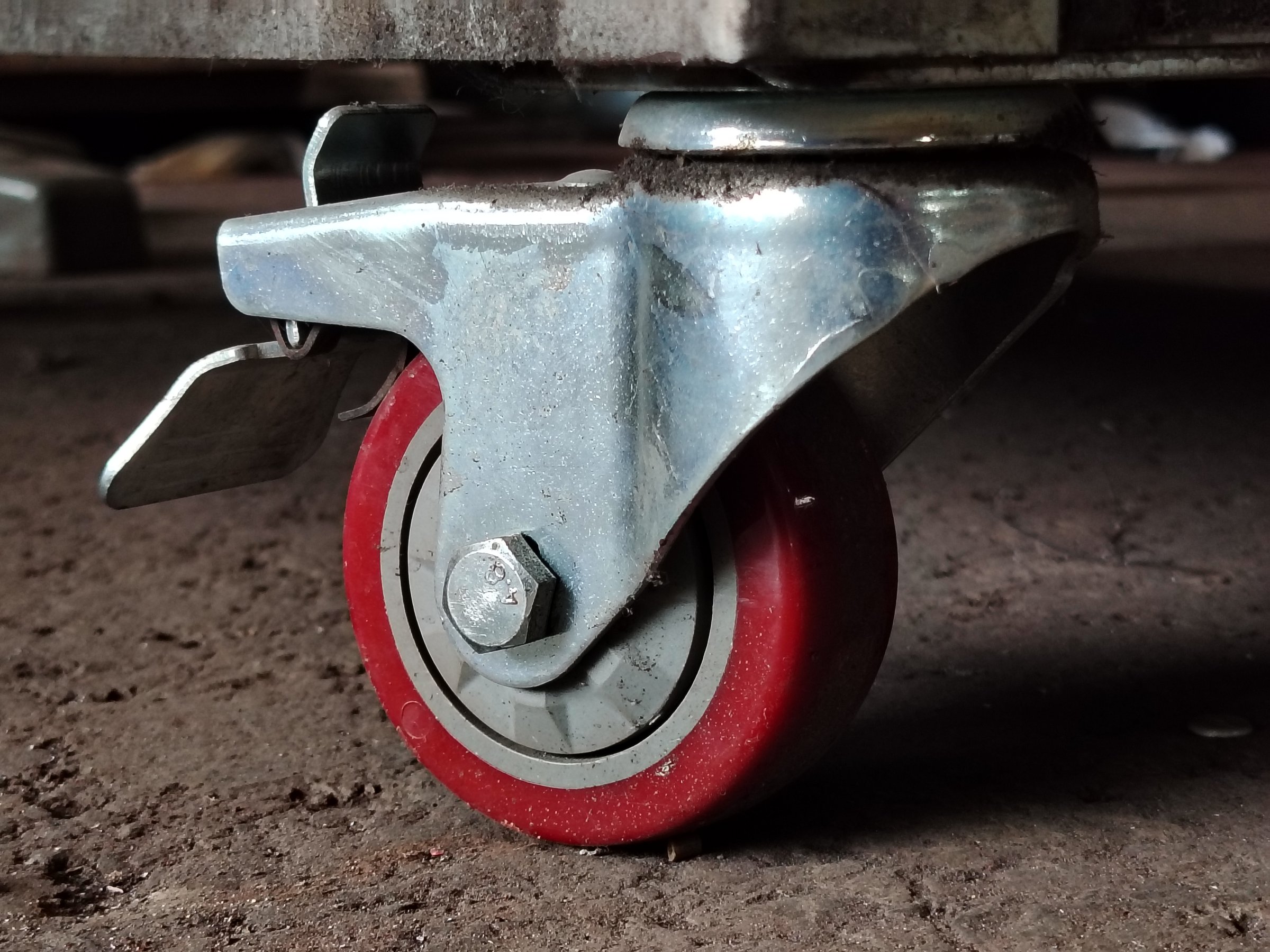 Heavy duty swivel caster wheel with red polyurethane tread and lock mechanism.