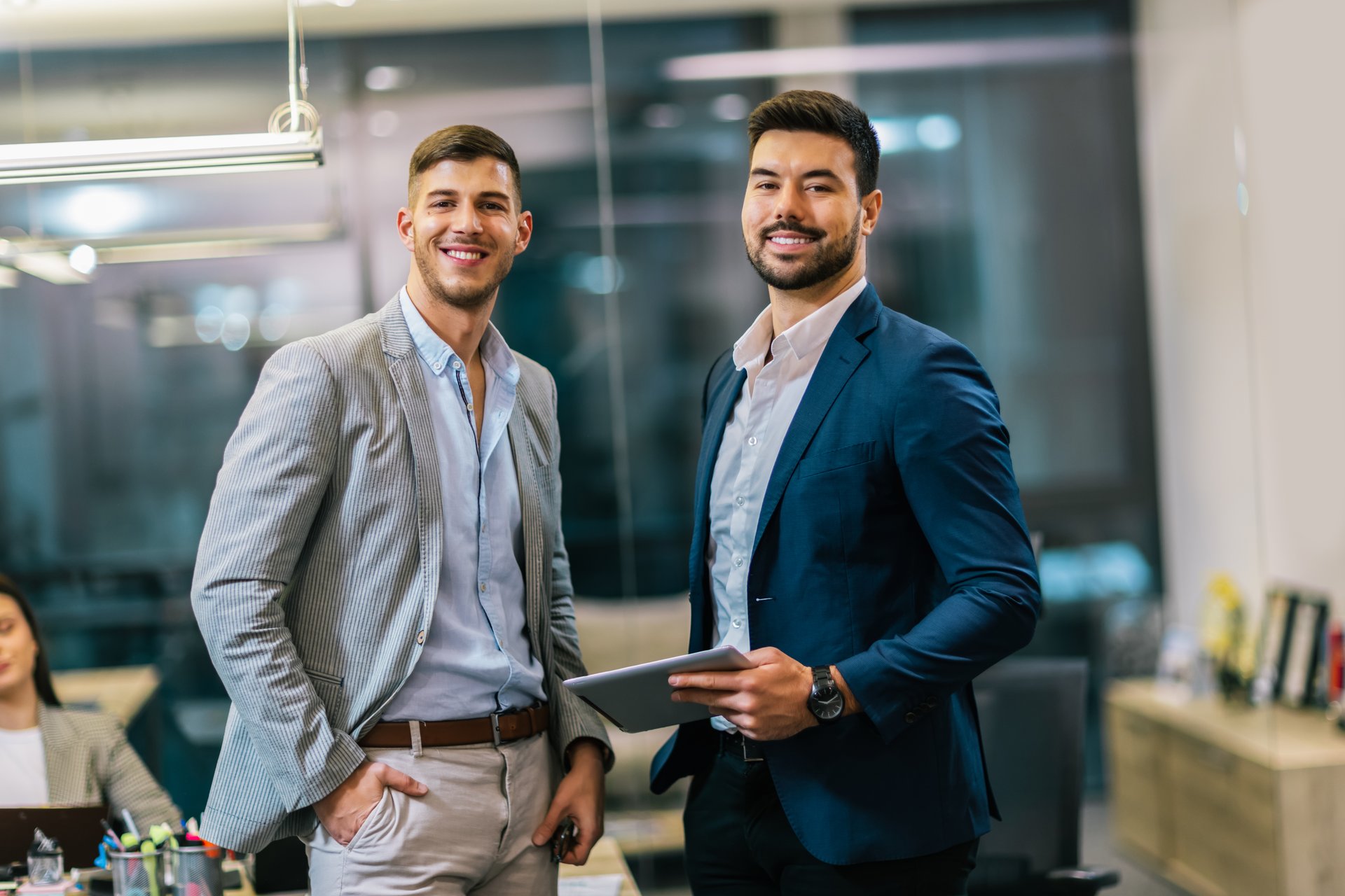 Two colleagues talking in corridor. Using tablet for the job.