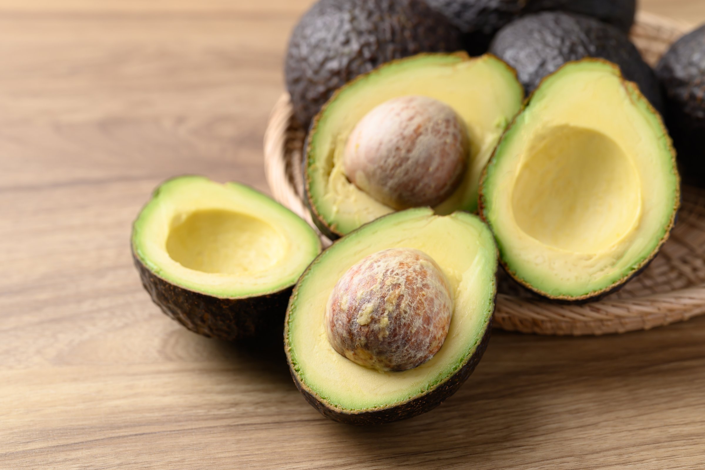 Ripe Hass avocado fruit in basket on wooden background, Healthy fruit