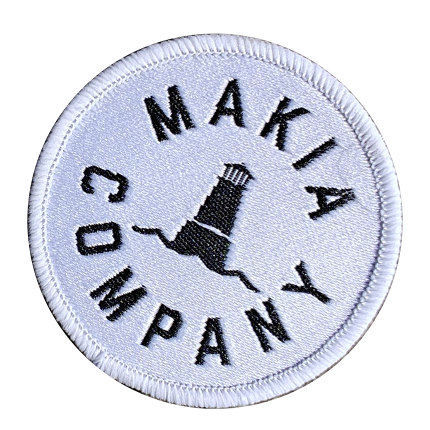 Round embroidered patch with the text Makia Company and an illustration of a lighthouse.