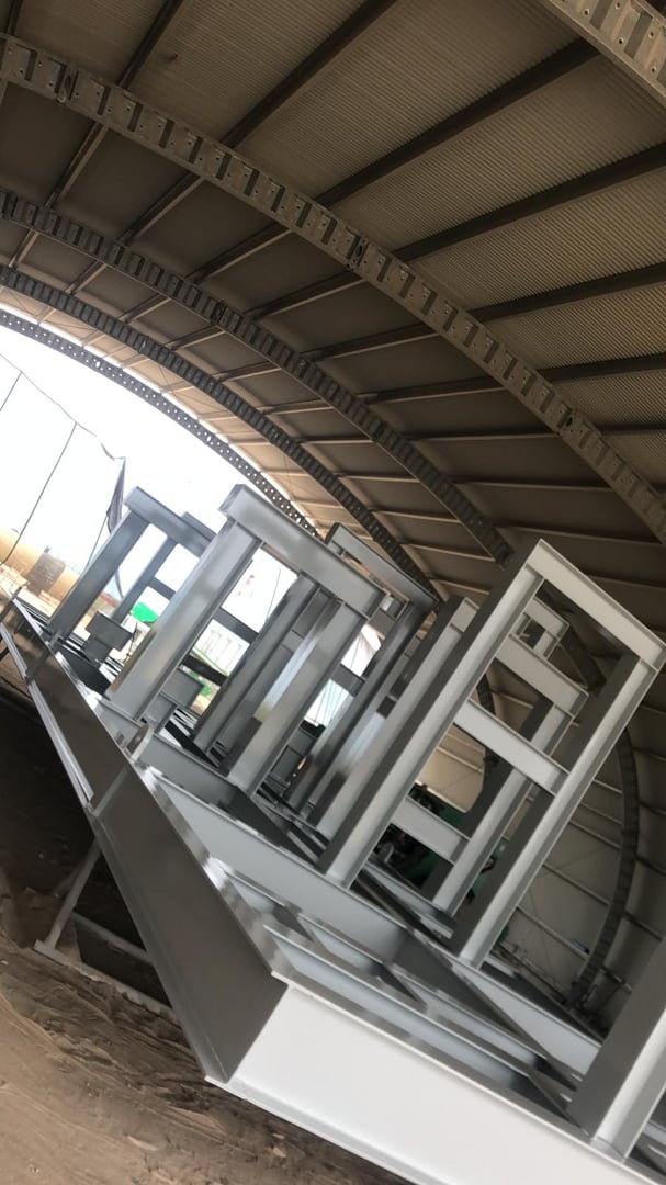 Interior of a large industrial warehouse with metal framework structures under construction.