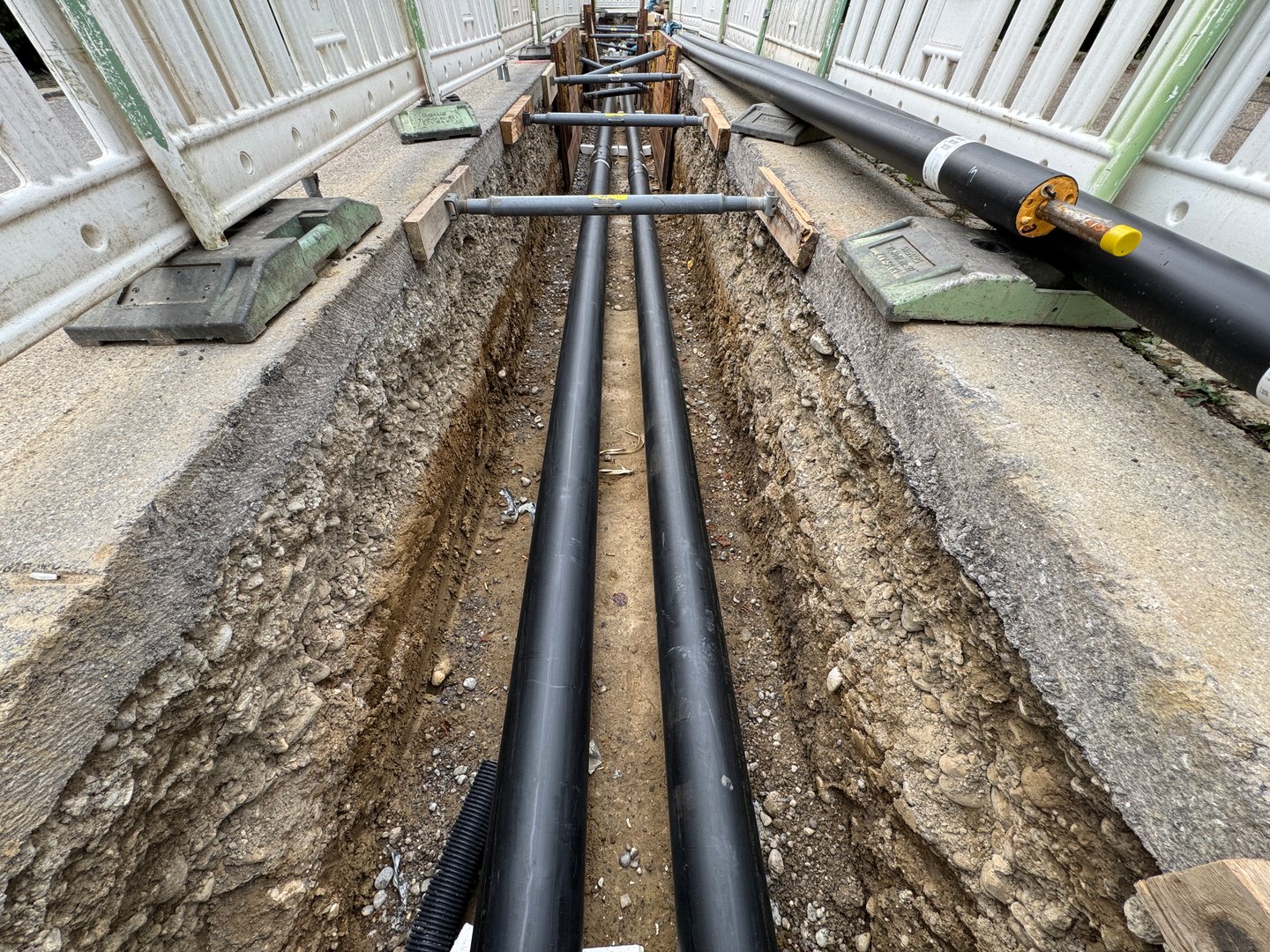 This view shows neatly laid underground pipes in a trench at a construction site, ready for installation