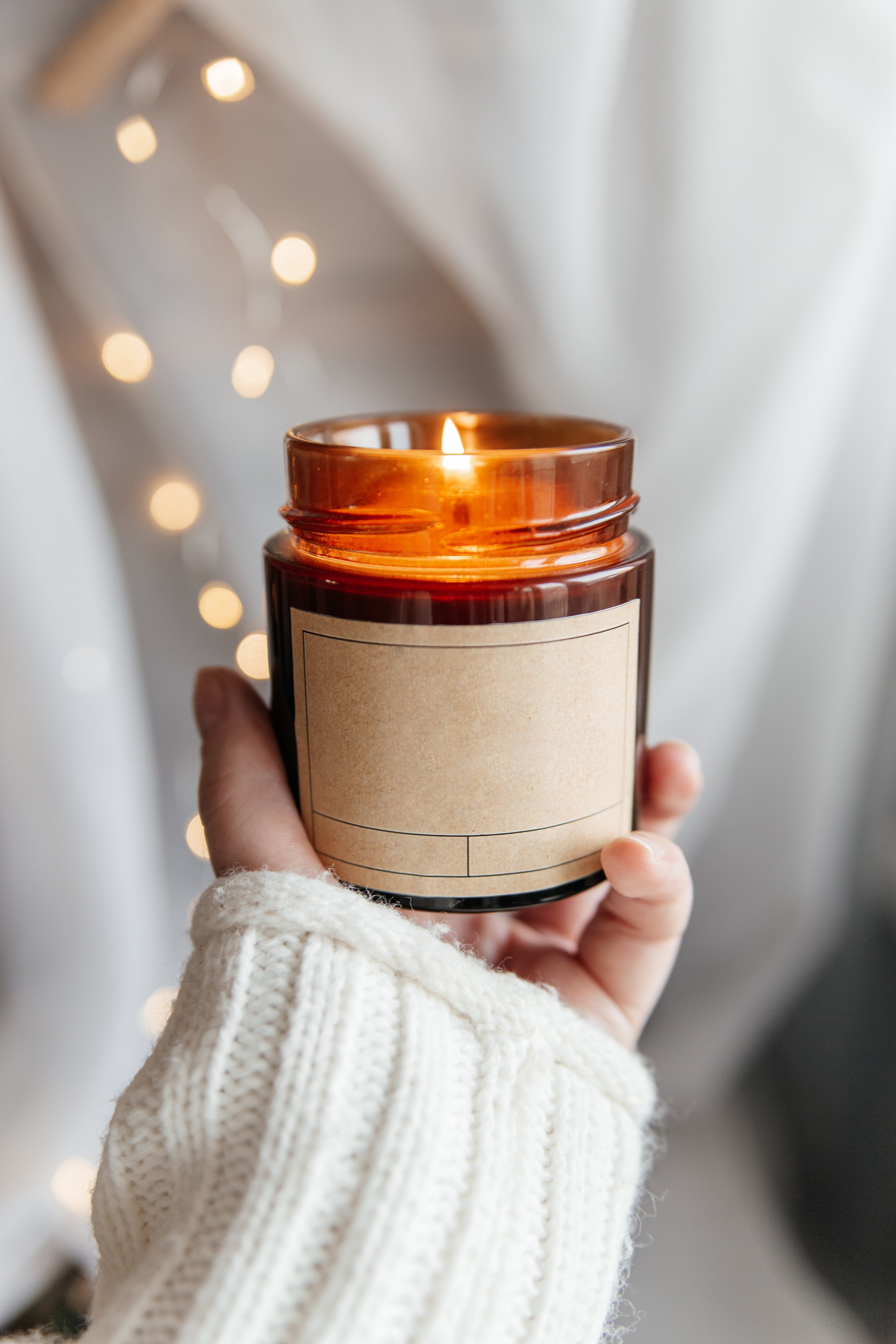 Hand holding soy candle in brown glass jar