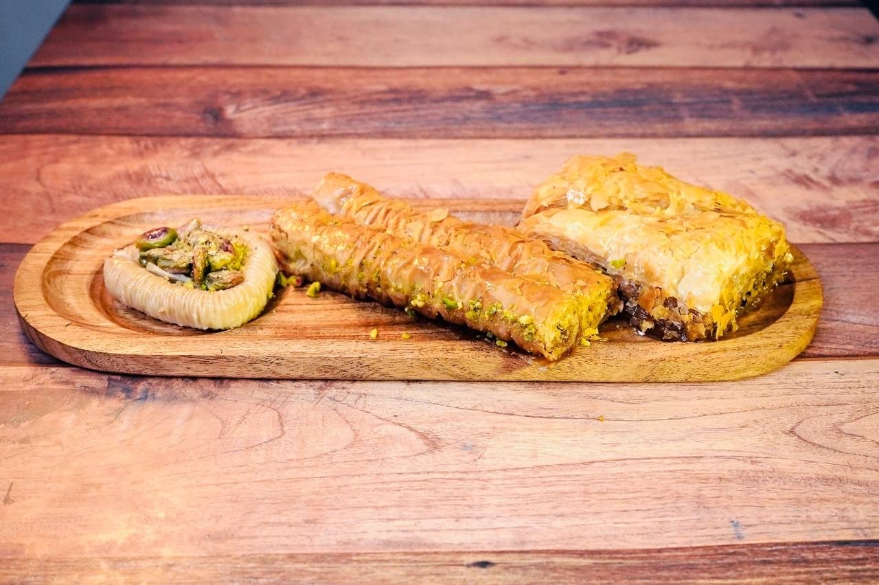 Baklava with walnuts and honey on a beige background. Traditional East desert in wooden dish. Copy space.