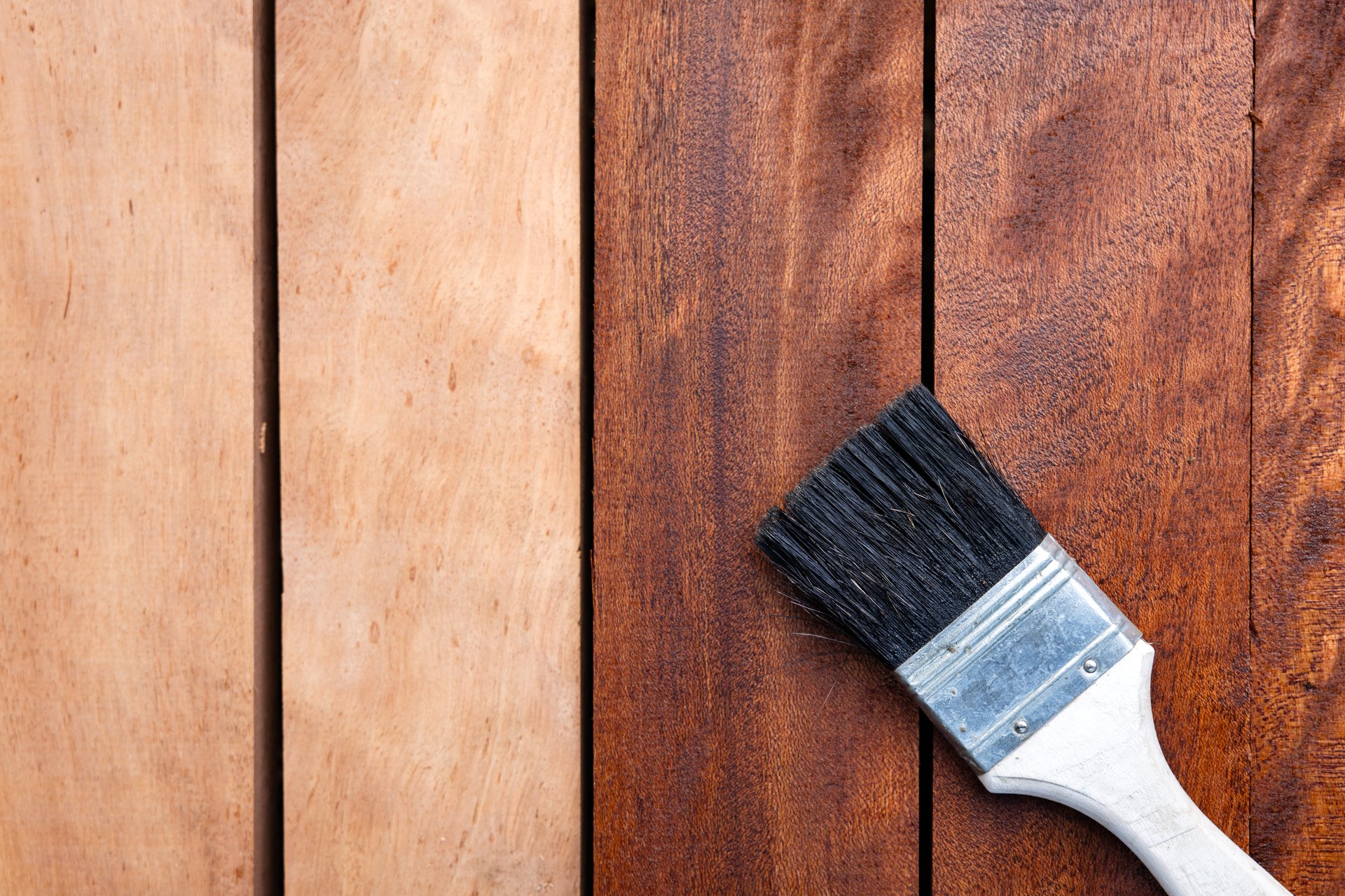 Close up paint brush apply varnish on lumber or wood product in top view. Before after paint look darker brown color to improve, protective or coating stain grain surface suit for concept background.