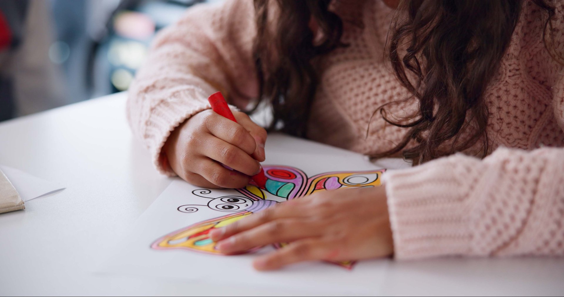 Color, crayon and hands of child in classroom, growth and development of student in school and paper. Art, table and creative with butterfly, skills and kid in kindergarten, youth and learning