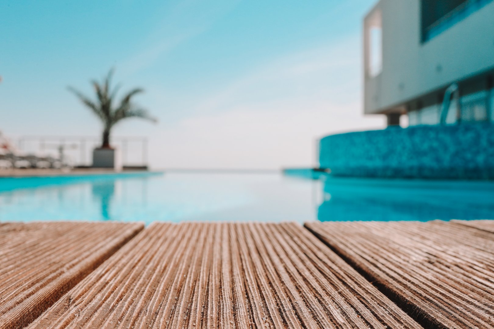Empty wooden deck with swimming pool , Beautiful minimalist pool side view with clear blue sky . Vintage filter color apply .