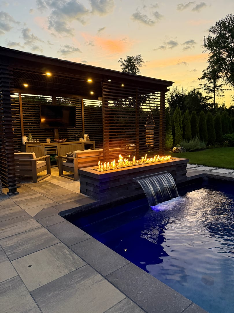Modern outdoor patio with fire pit, seating, and greenery
