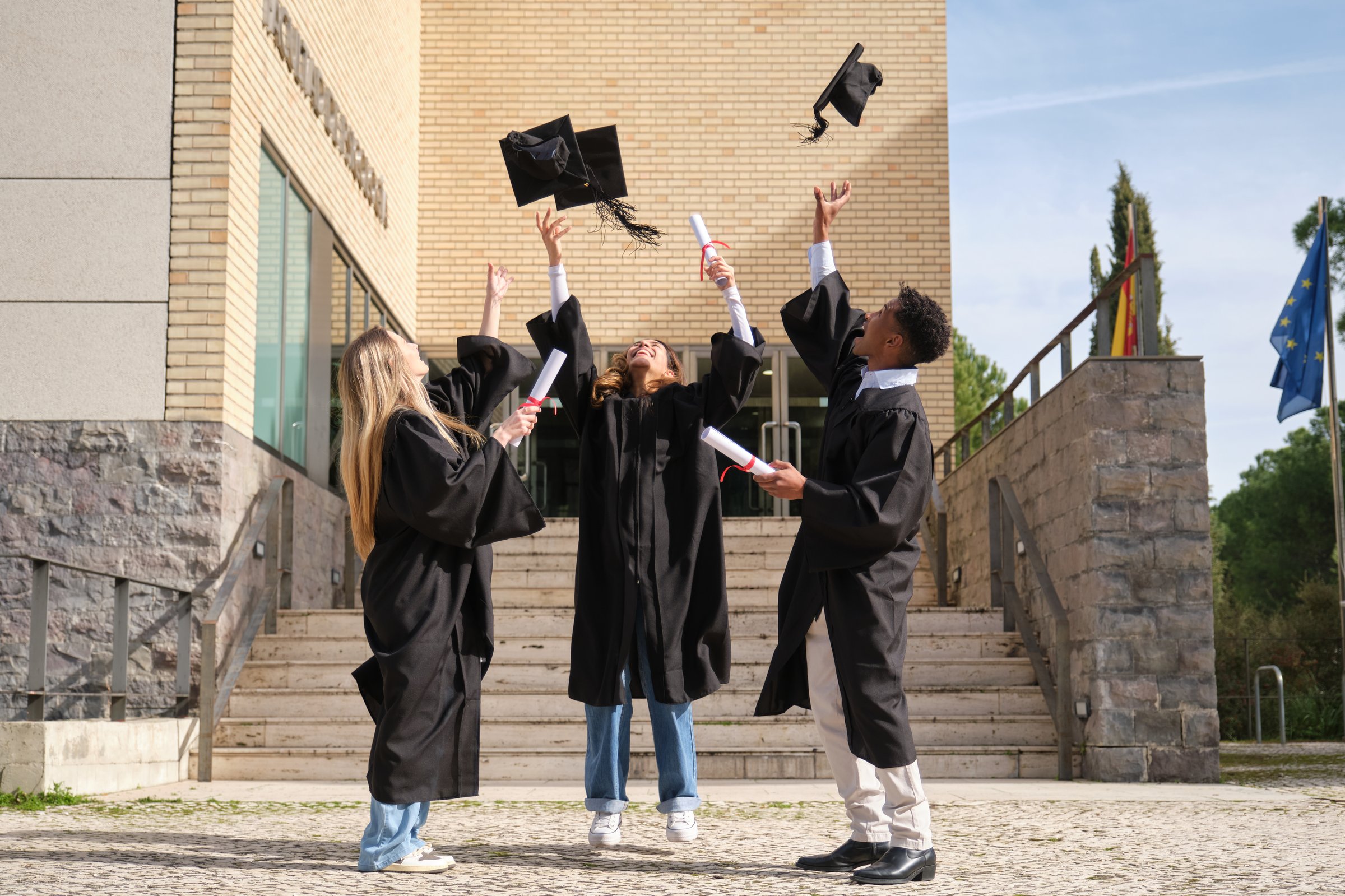 Group of cheerful multi-ethnic graduating students throwing their graduation caps in the air