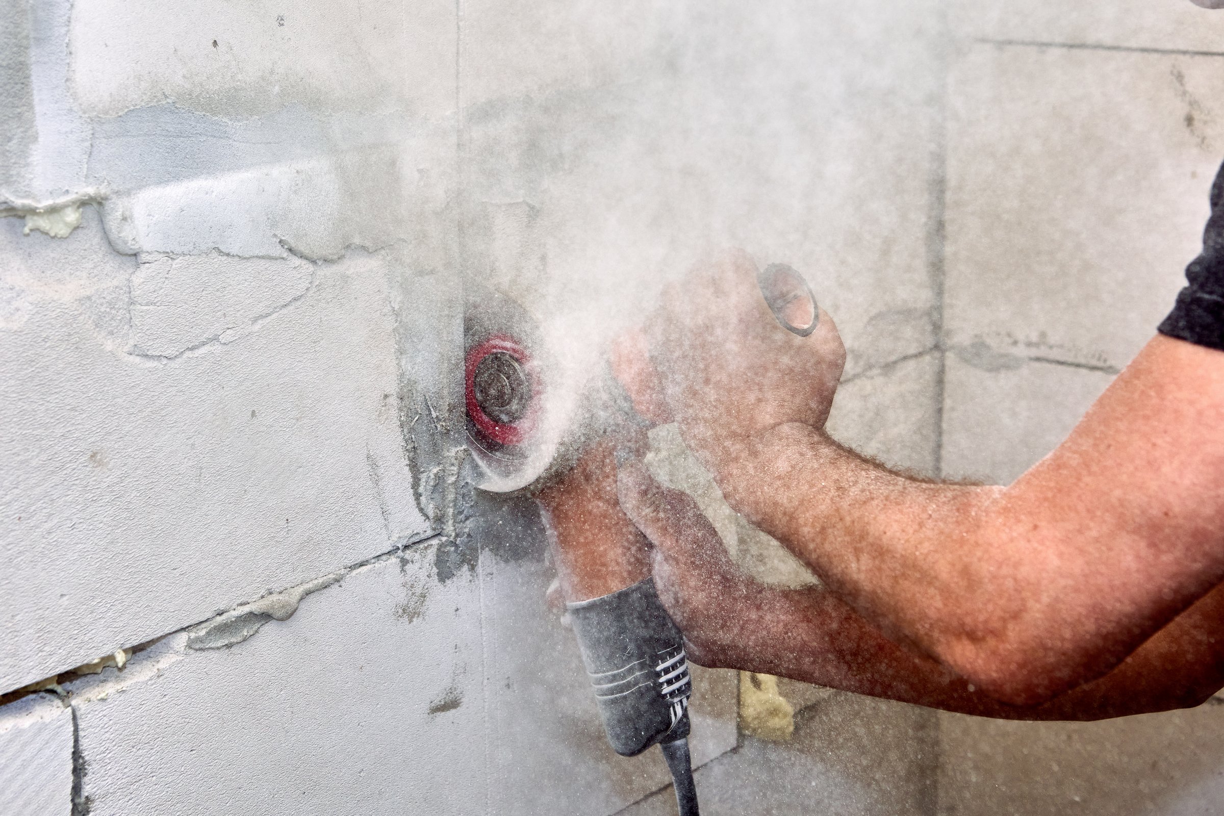 Cutting masonry with angle grinder and concrete cut saw. Electric hand power tool for dry cutting creates cloud of dust hazardous to health.
