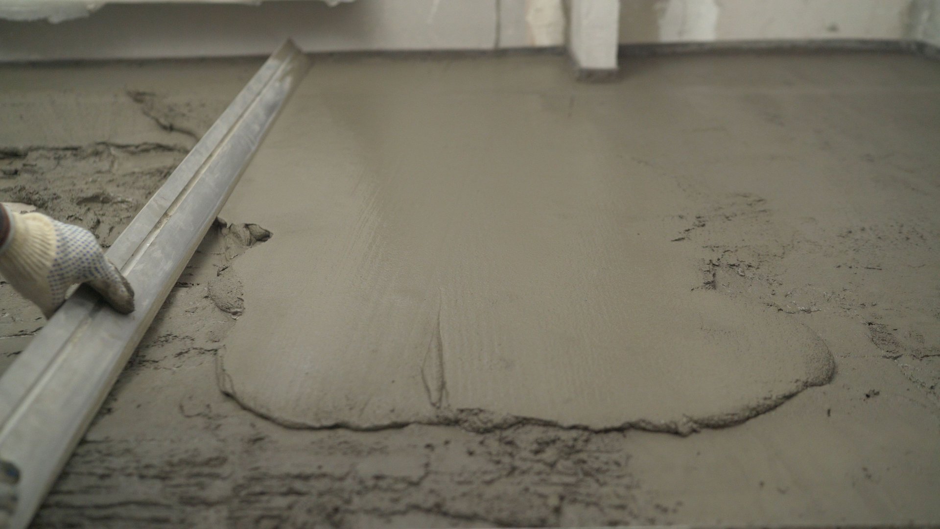 Leveling the floor with mortar and trowel. Laying self-leveling floor screed and uniformly spreading with a tool. Leveling the uneven floor.