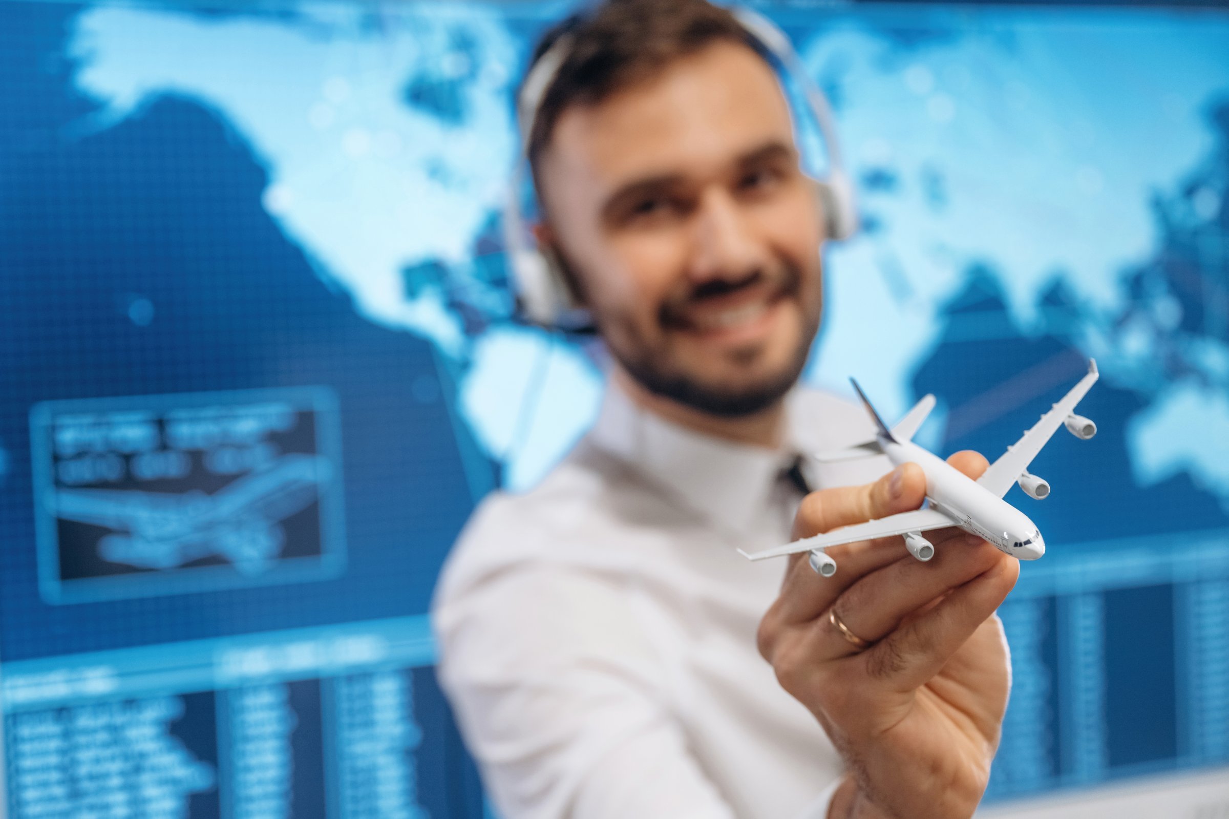 Standing and smiling. Man is holding toy plane, in airline company.