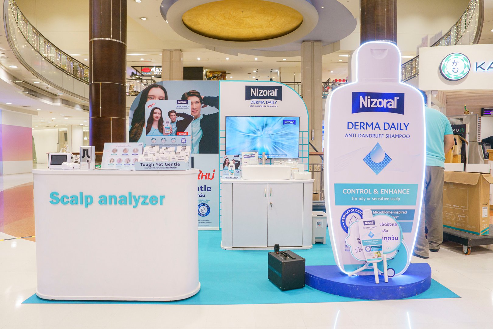 Nizoral shampoo promotional booth in a mall with large bottle display, scalp analyzer, and brand posters.