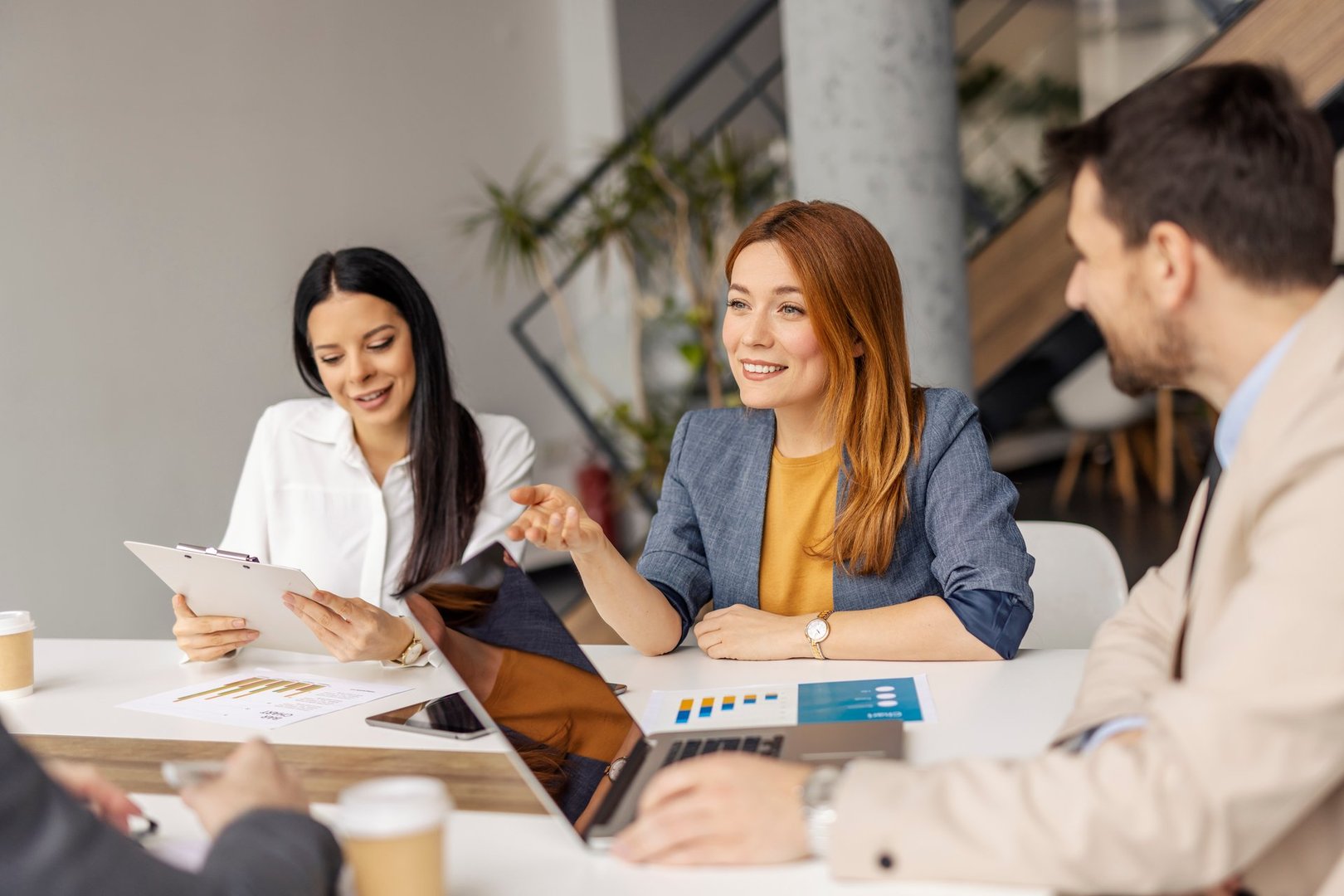 Businesswoman sitting on a meeting at boardroom and discussing analyzes and paperwork with coworkers.