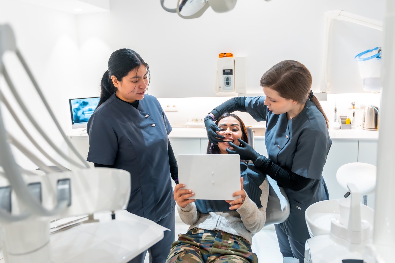 Dentist shows a patient the results of her teeth whitening treatment, using a mirror in a modern dental clinic