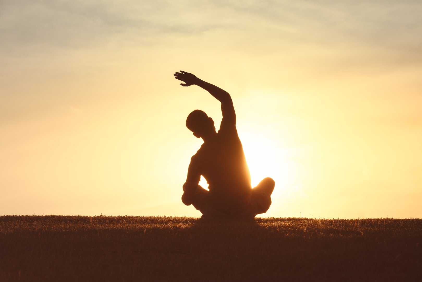 Young man stretching and practicing yoga at sunrise.