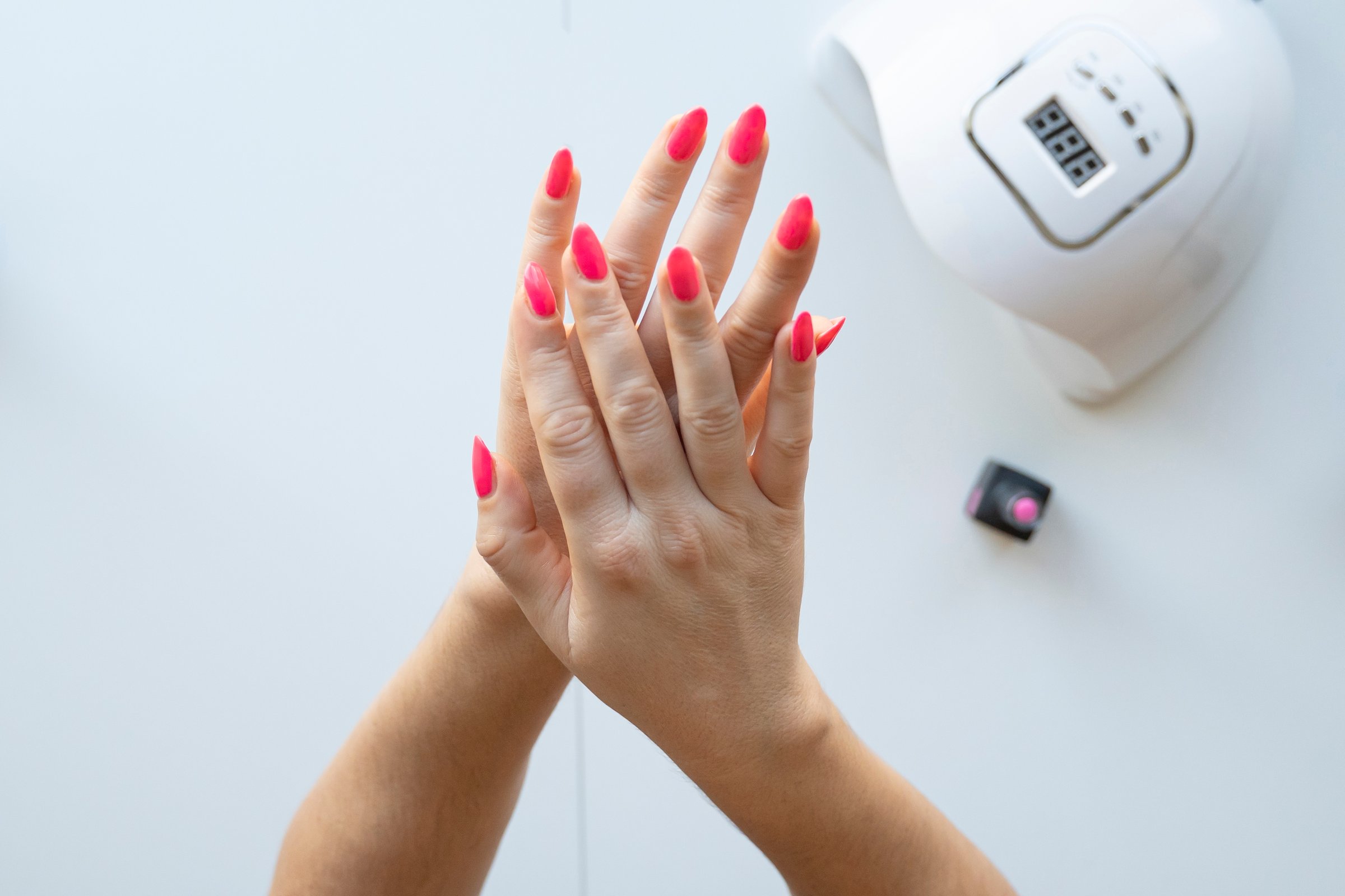 Woman's hand with pink nail polishand accessories and tools for hardware manicure and receiving nail procedure stock photo
