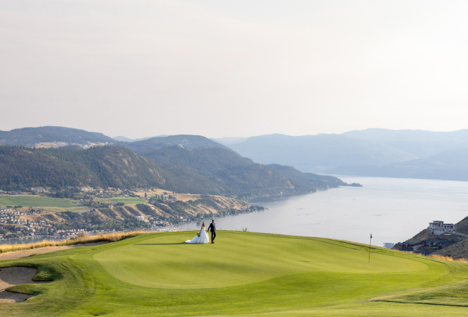 A man and woman are holding a bouquet of flowers. The man is wearing a suit and tie, and the woman is wearing a wedding dress. The flowers are pink and white, and they are arranged in a vase