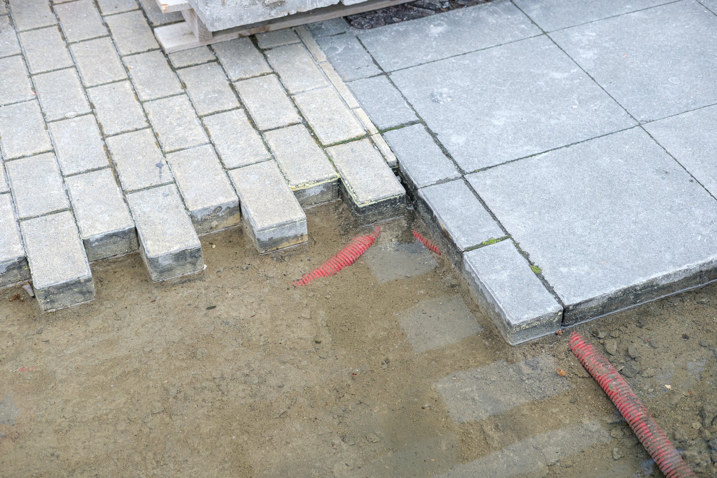 paver installation in progress with flexible work tubs, preparing ground for garden paver pathway construction